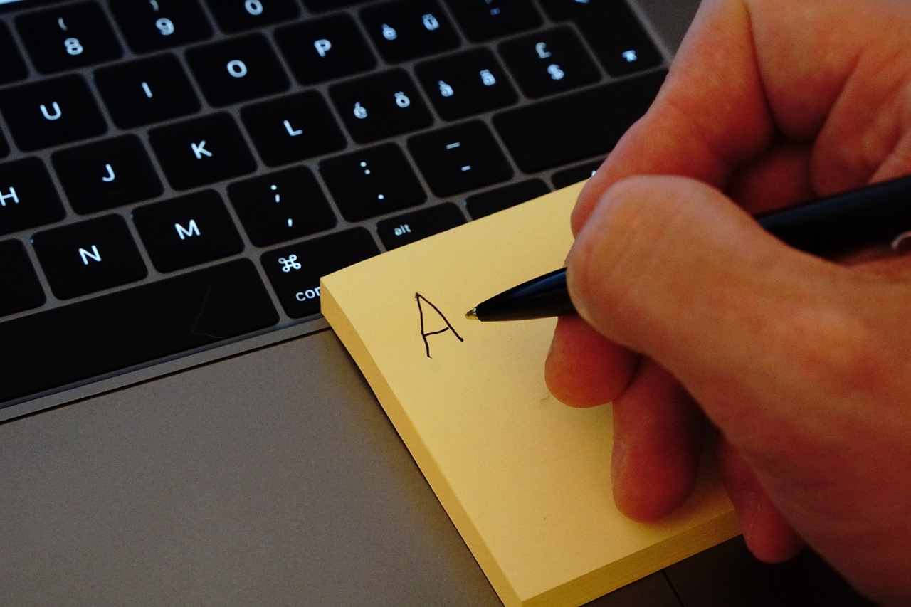 Writing on a sticky note on a laptop